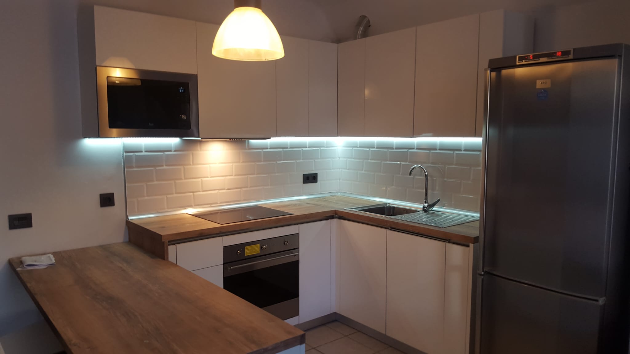 Cocina con iluminación LED bajo los armarios altos y punto de luz colgante