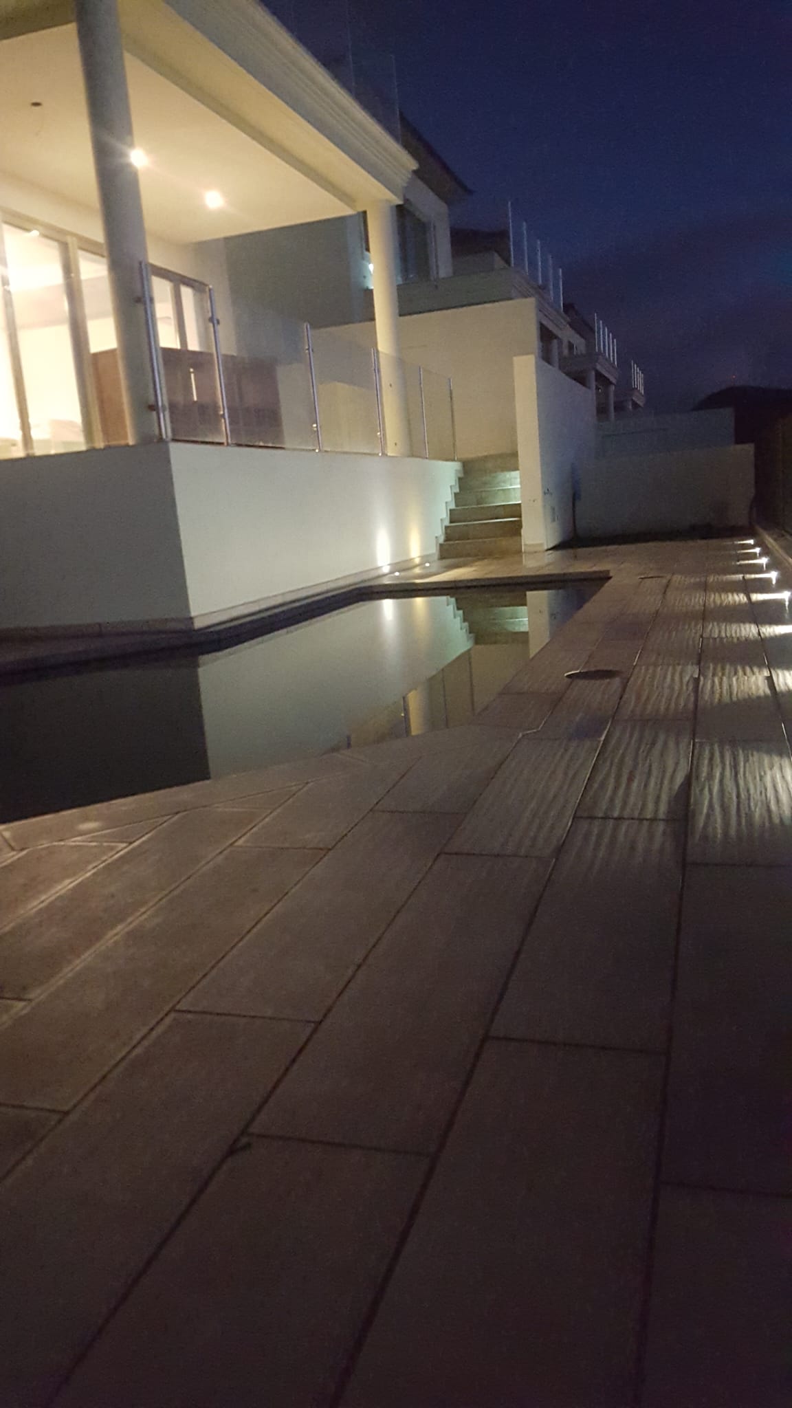 Iluminación nocturna de piscina, escalera exterior y terraza en una vivienda